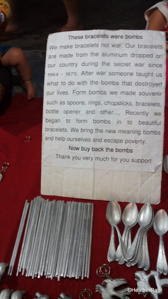 Vendor at night market selling , bracelets, spoons, rings, bottle openers and more made from aluminum fragments of bombs dropped on Laos.